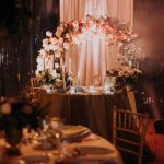 Tavolo degli sposi allestito con un arco floreale e candele scenografiche